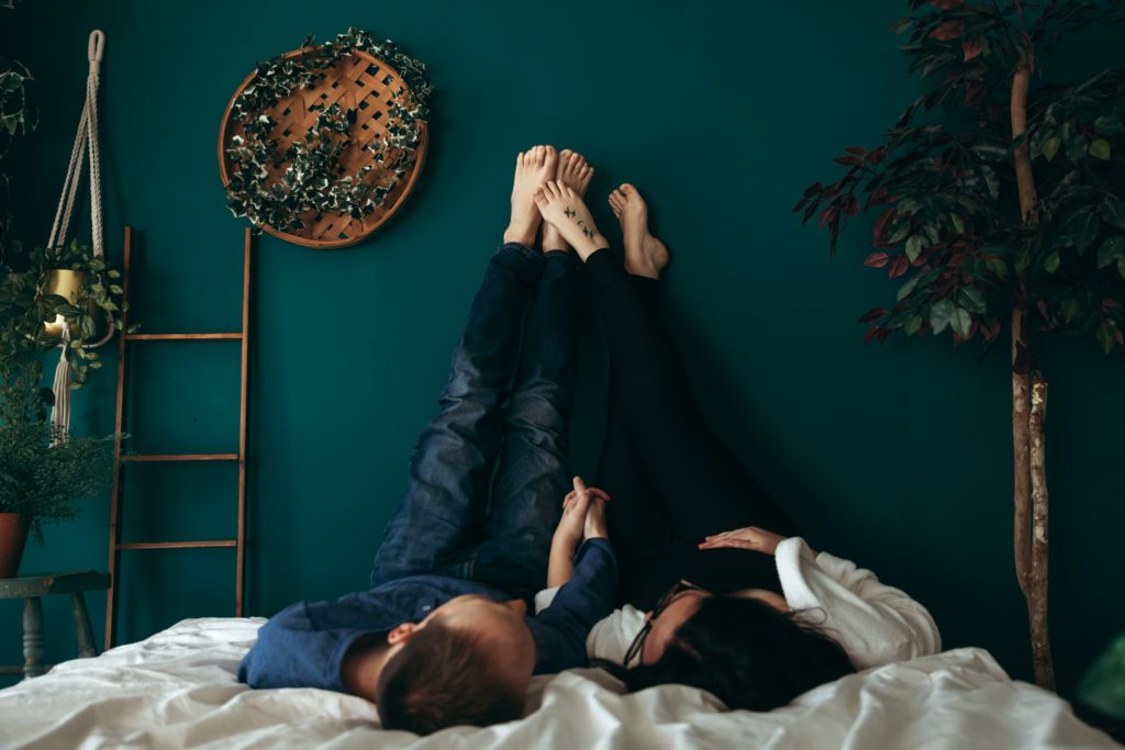Couples photoshoot lying on bed with fit on wall