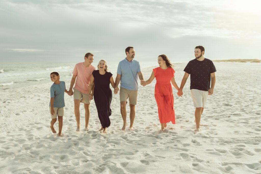 extended family holding hands on the beach while walking