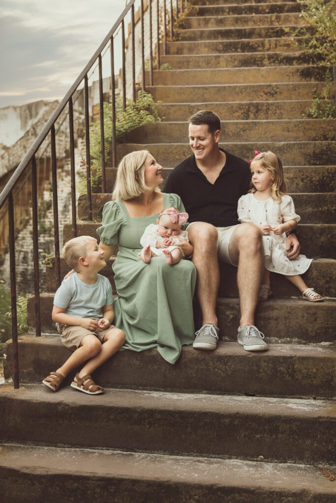 Family sitting and looking at each other on the steps during a photoshoot